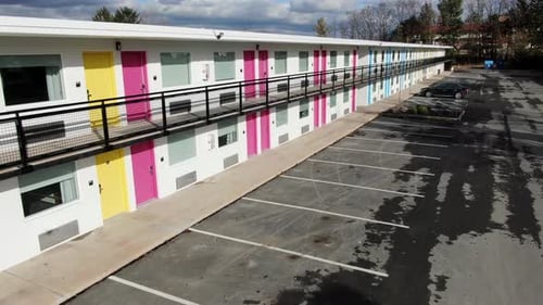 Empty deserted unoccupied hotel motel in Lancaster PA, pink and yellow doors, aerial dolly shot
