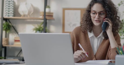 Young Office Worker Speaking on Mobile Phone and Writing in Notebook Working in Office Alone