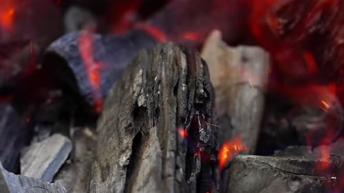 Flaming charcoal with glowing embers and sparks flying in a close-up shot