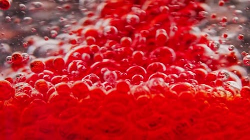 Makroaufnahme von roten Blasen, die sich in Wasser mischen und herumschweben