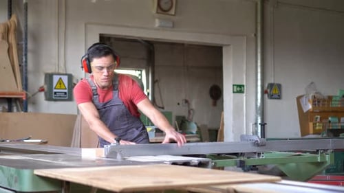 Man cuts wood on table saw in workshop