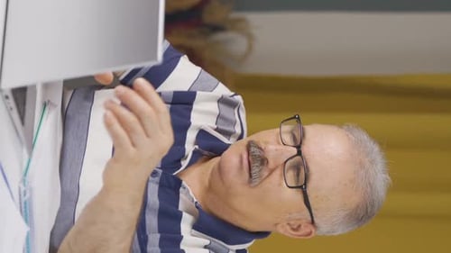 Vertical video of Home office worker old man attending online business meeting.
