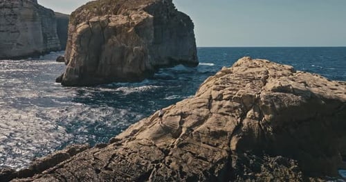 Aerial View of a Girl Climbing a Rock Near the Seashore