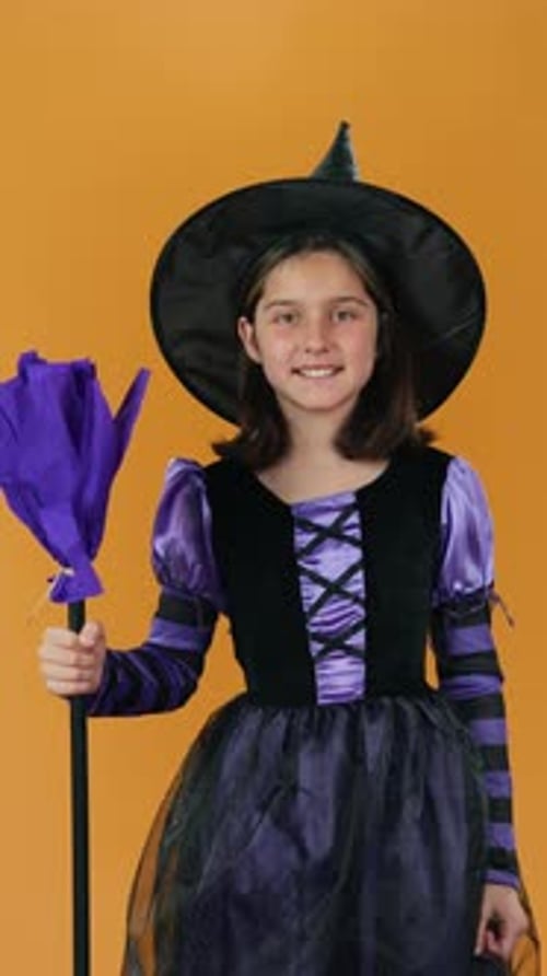 Young Girl in Halloween Witch Costume with Toy Broom