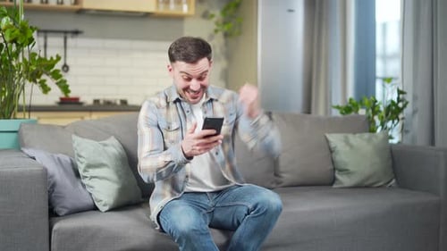 Excited Man Looking at Phone on Couch