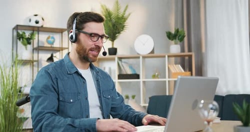 Man Telecommuting Using Laptop and Headset