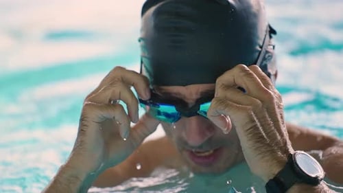 A Determined Swimmer Adjusts His Goggles in an Aquatic Environment Preparing for a Rigorous Training