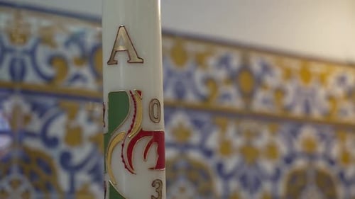 Paschal candle in church setting, Decorative tilework and engraved ceramic details