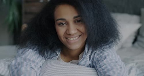 Smiling Woman Relaxing on Pillow in Bedroom