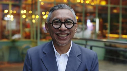 Stylish Positive Senior Manager Wearing Glasses and Grey Suit Looking at the Camera