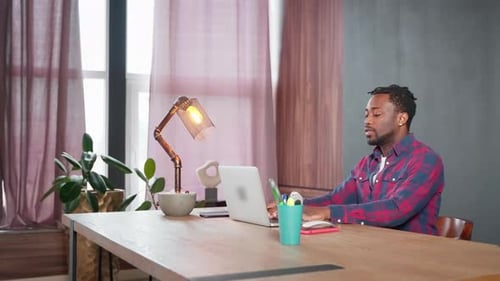 African Amerian Man Working on Laptop Sitting at Workplace in Home Office