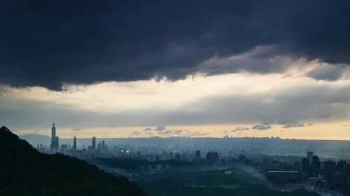 The evening glow on the mountains. Dramatic dynamic dark clouds over the city.