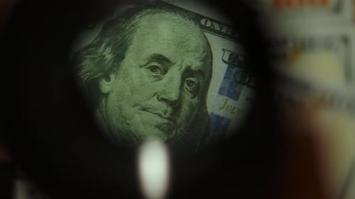 Examining One Hundred Dollar Bills with a Magnifying Glass