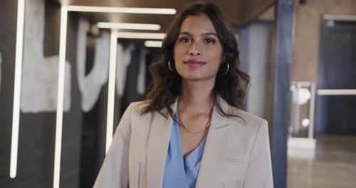 Portrait of happy biracial casual businesswoman in office, slow motion