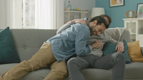 Joyful Young Men Embrace on Living Room Couch