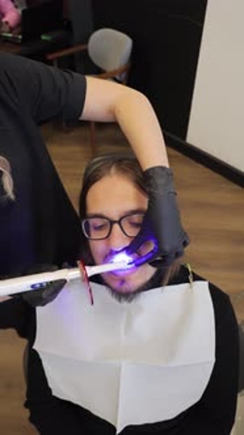 Dentist Using a Uv Light Lamp on a Male Patient