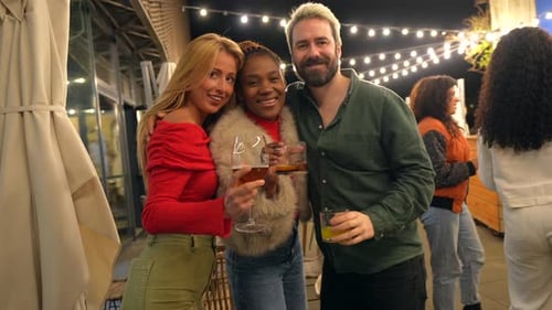 Friends Smiling Toasting at Camera in a Bar at Night