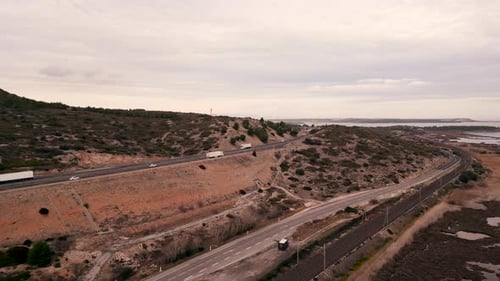 Vehicles Drive on a Road Next to a Lake