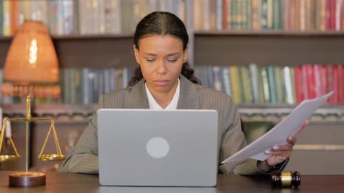 African Female Lawyer Doing Paperwork on Laptop in Courtroom