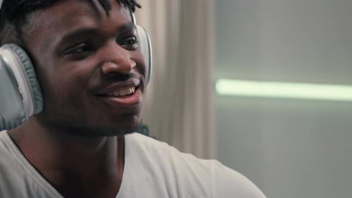 Smiling Man Listens with Headphones in Room