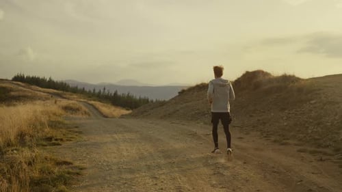 Back View Active Man Running in Mountains. Male Runner Training on Ground