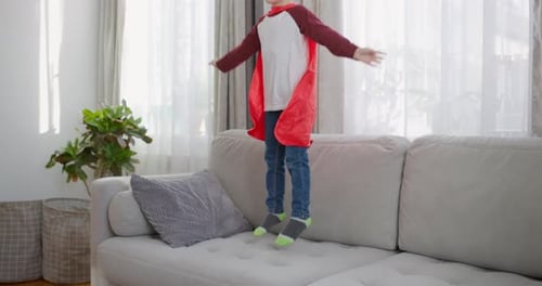 Boy in Mask Jumping on Couch as Superhero