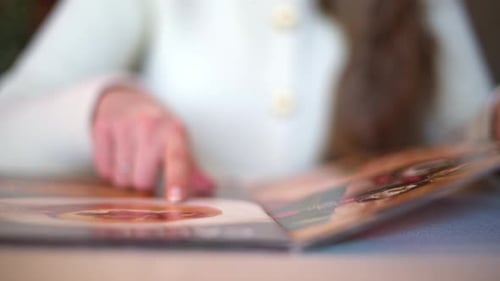 Woman hands in restaurant choosing food in menu