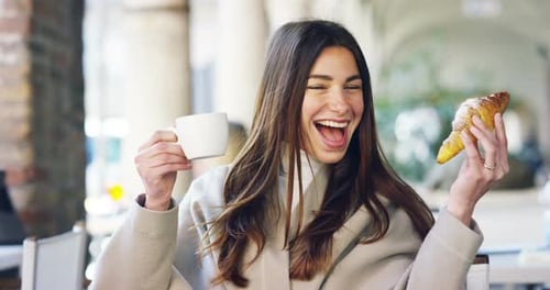 One morning a beautiful elegant woman eats breakfast at the outdoor bar with a coffee and croissan