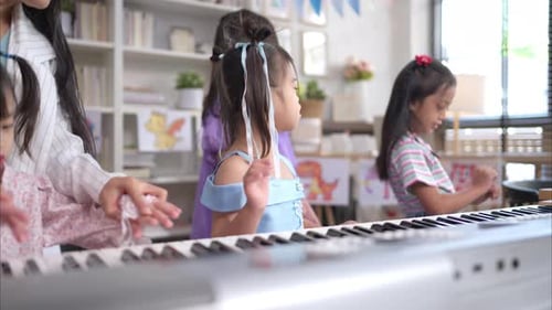 Teacher Helping Child Play Piano in Classroom