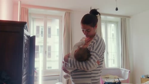 Woman in Striped Pajamas Breastfeeding Baby Indoors