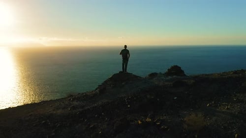 Silhouette of Hiker Man Standing on Mountain Top at Sunset