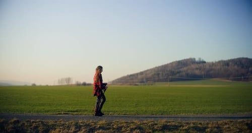 Woman Walking with Sticks on Rural Path