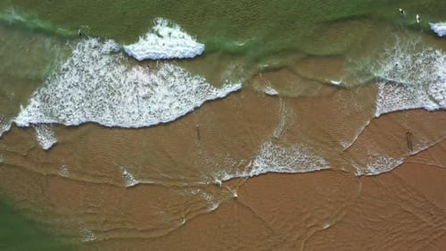 Aerial View of Waves Crashing on Sandy Beach on Sunny Day