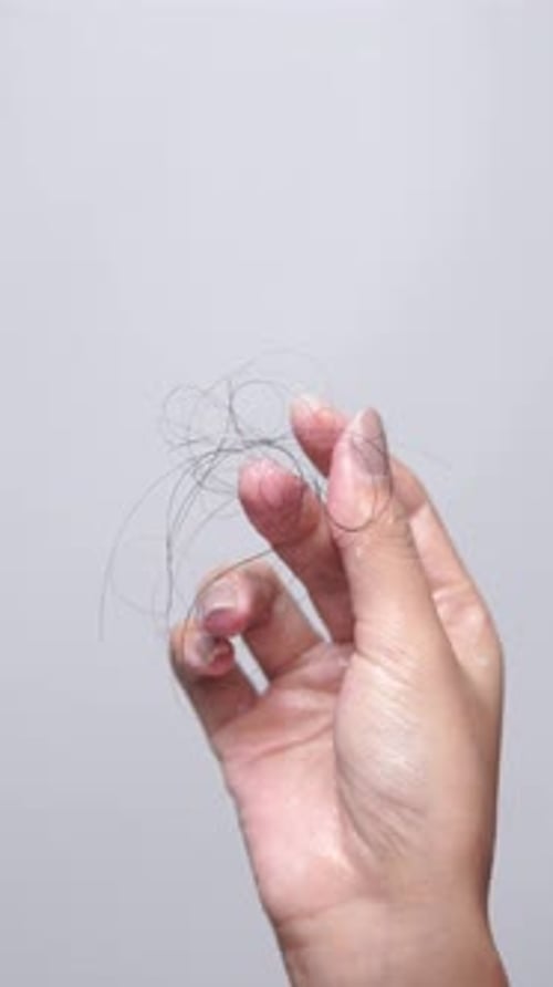 Close up of Asian young woman holding her fall hairs and showing to the camera.