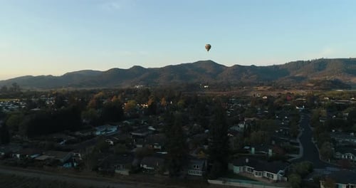 panorama aerial of a hot air balloon taking flight over a small town