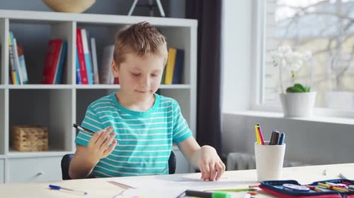 Boy is Doing His Homework at the Table Cute Child is Learning at Home with the Help of Textbooks and