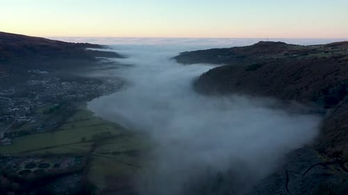 Aerial view of a lake and town covered by fog and clouds at sunset