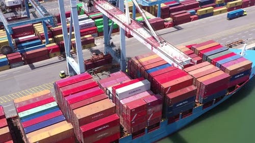 Schiffscontainer, der von einem Portalkran auf ein großes Containerschiff geladen wurde.