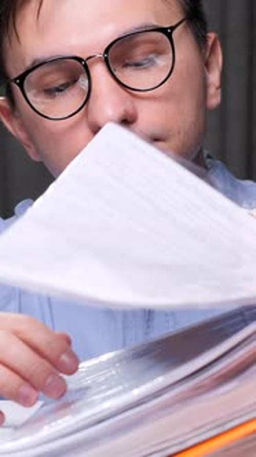 Vertical Video Accountant Searching Documents in Stack of Folders at Office Desk