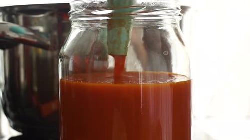 Prepared tomato sauces are placed in a jar for canning, close up.