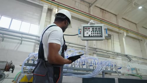Industrial Black Worker Programmer Checking the Production Line with Tablet
