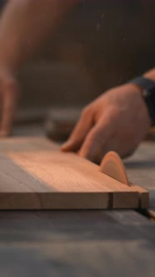 Man Cutting Wood Plank With Saw in Workshop
