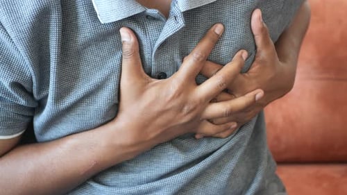 Young Man Suffering Pain in Heart and Holding Chest with Hand