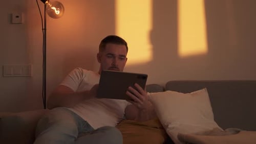 Man relaxing on sofa using his tablet device