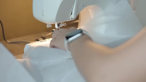 Nahaufnahme weiblicher Hände, die eine Nähmaschine zum Nähen von Stoff verwenden