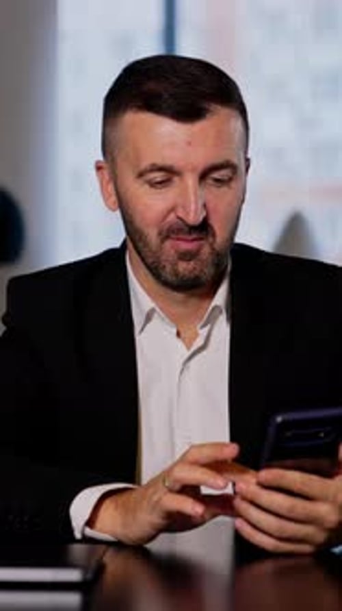 Man in Suit Using Smartphone Indoors at Table