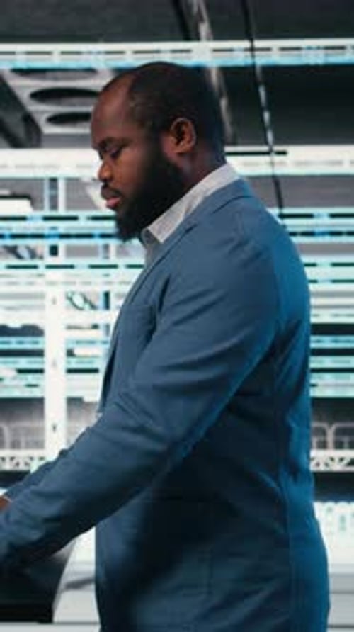 Vertical Video Technician at Server Hub Workspace Desk Using Laptop to Do Maintenance Tasks