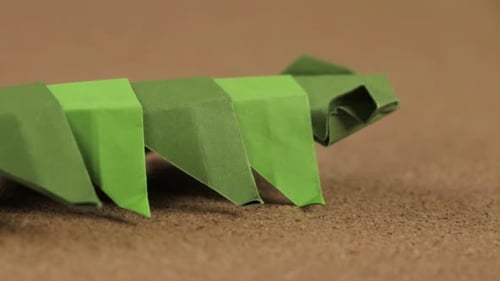 Paper worm made with the origami technique. Cork surface for crafts. Close up. Long video.