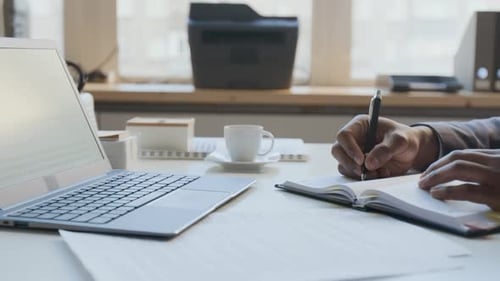 Anonymous Black Businessman in Suit Writing in Notebook in Office
