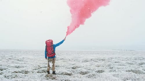 Person Holding Smoke Flare in Snowy Landscape